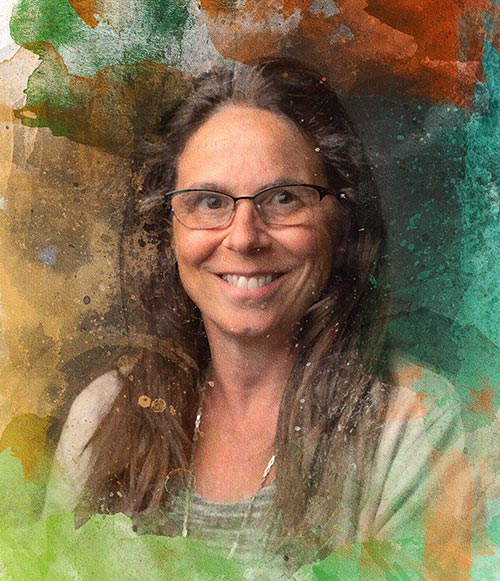 smiling close-up of Tiziana, with colorful paint splashes at the edges. Tiziana is a middle age woman, wearing glasses, with long, brown hair and brown eyes
